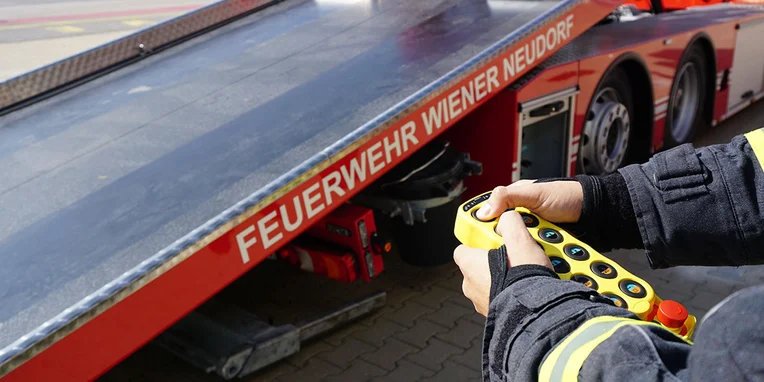 Feuerwehrmann bedient Steuerung für die Auflagefläche des Mercedes-Benz Econic 2635 Abschleppwagens