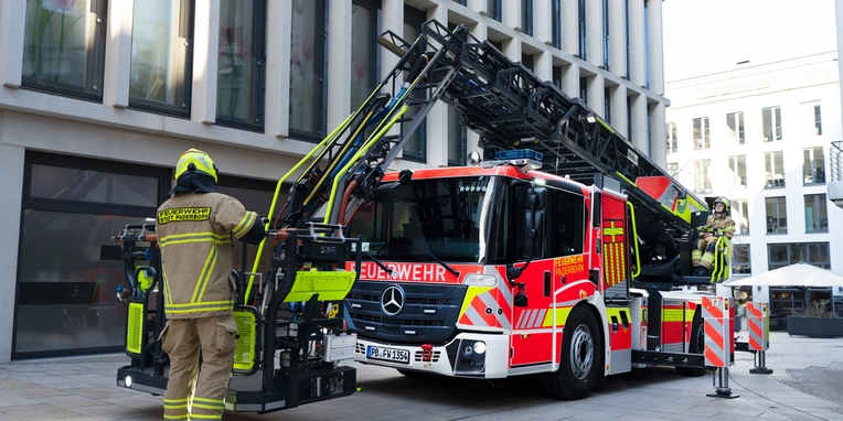 Feuerwehrmann betätigt den Kranarm eines Feuerwehrfahrzeugs in der Stadt.