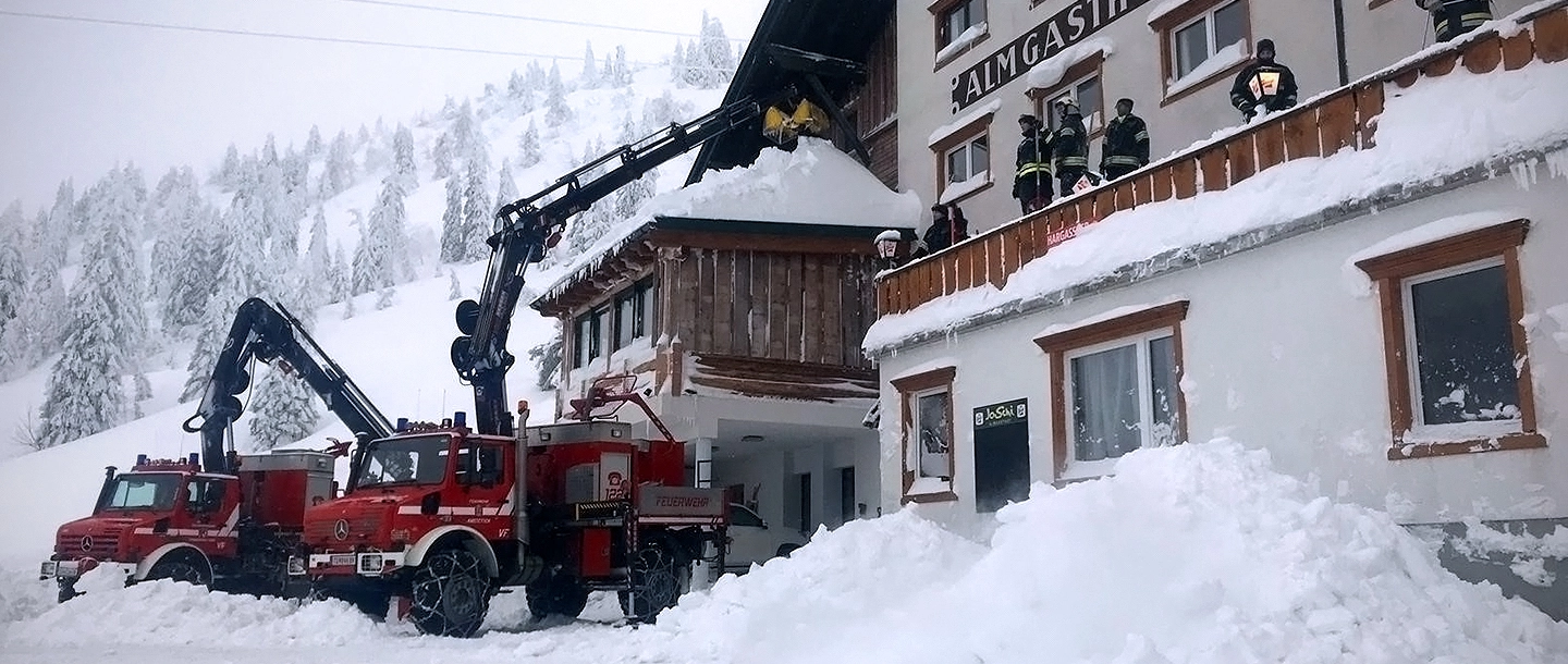 Im österreichischen Winterchaos räumt Unimog zugeschneite Gebäudedächer.