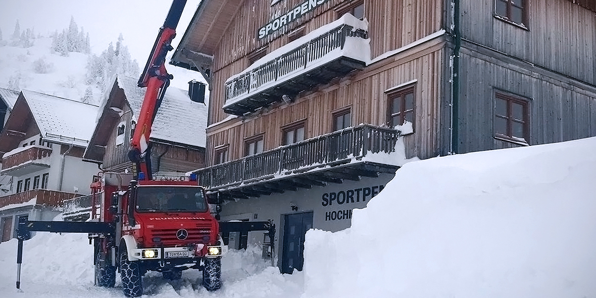 Im österreichischen Winterchaos räumt Unimog zugeschneite Gebäudedächer.